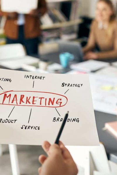 Close-up of businessman talking to his colleagues about marketing plans while working on new project at casual office.